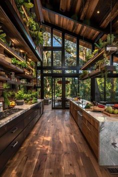 an open kitchen with wooden floors and lots of plants on the counter tops in front of large windows