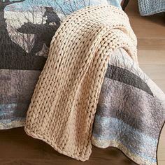 a bed covered in a blanket and pillows with animals on the coverlet next to it