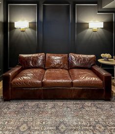 a brown leather couch sitting on top of a rug in a living room next to two lamps