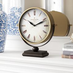 a clock sitting on top of a white mantle next to vases and other items