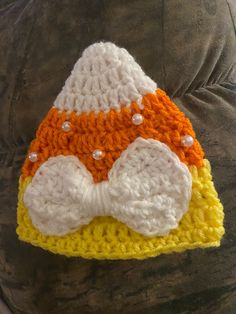 a crocheted hat with an orange and white bow on the front, sitting on someone's back