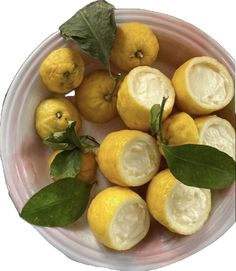 a bowl filled with lemons and leaves on top of a table