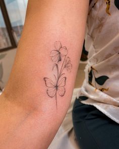 a woman's arm with a butterfly and flower tattoo on the left side of her arm