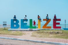 children are sitting on the letters that spell out belize in front of the ocean