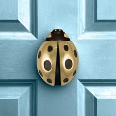 a ladybug shaped door knocker on a blue door with black polka dots