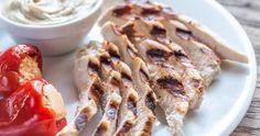 grilled chicken with ketchup on a plate next to a small bowl of ranch dressing