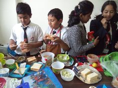 several children standing around a table with food on it