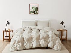 a bed with white comforter and pillows in a room next to two nightstands