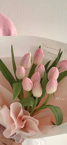 a bouquet of pink tulips and greenery in a paper bag with a note on it