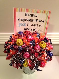 a vase filled with lots of candy sitting on top of a white table next to a sign