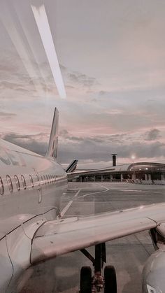 an airplane sitting on the tarmac at dusk with clouds in the sky behind it