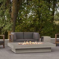 a fire pit sitting on top of a patio next to two chairs and a couch