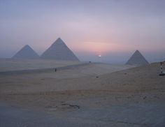 three pyramids in the desert at sunset