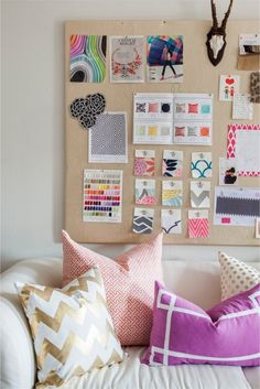 a living room filled with lots of pillows and pictures hanging on the wall above them