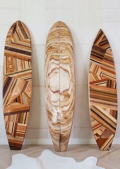 three wooden surfboards are lined up against the wall