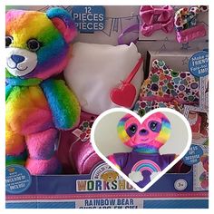 there is a rainbow bear with a heart on the front and other items in the back