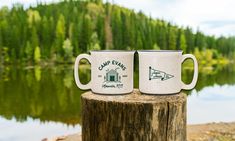 two coffee mugs sitting on top of a tree stump