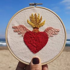 someone holding up a hand embroidered heart with wings