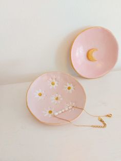 two pink plates with daisies on them and a chain hanging from the bottom one