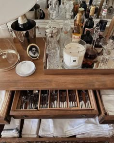 an open drawer in front of a mirror filled with bottles and glasses