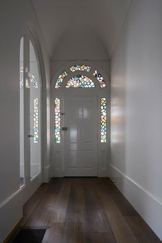 an empty hallway with stained glass windows and wood flooring in front of the door