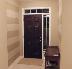 an empty entryway with a black door and striped walls