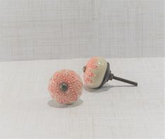 a pair of pink and white ceramic knobs sitting on top of a table next to each other