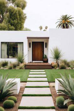 a white house with grass and plants in the front yard