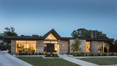 a modern house is shown at dusk with the lights on and grass in front of it