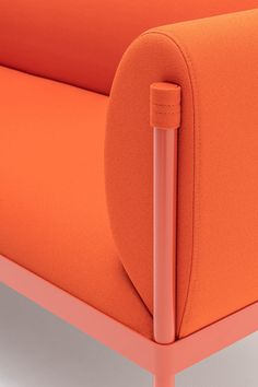 an orange couch with a metal arm rest on the bottom and back end, in front of a white background