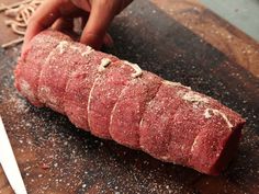 a piece of raw meat being sliced on a cutting board