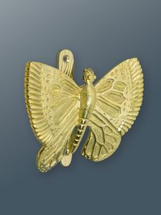 a golden brooch with a bird on it's back end and wings spread out