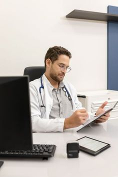 a man sitting at a desk in front of a laptop computer and holding a tablet