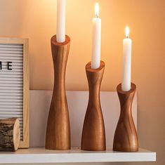 three wooden candlesticks sitting on top of a shelf