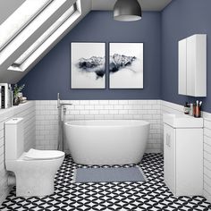 a bathroom with blue walls and black and white flooring, two pictures on the wall above the bathtub