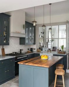 a kitchen with blue cabinets and wooden counter tops, along with an island in the middle