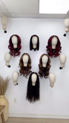 several wigs are arranged in a circle on a white wall next to a vase