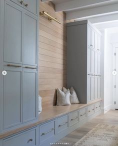 an empty room with white cabinets and pillows on the bench in front of the window