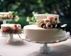 there are three cakes on the table with flowers and leaves on top, one is white