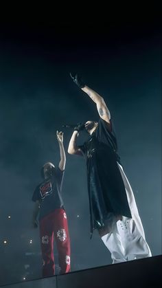 two men standing on top of a stage with their hands in the air