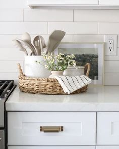 a basket filled with utensils and flowers on top of a white kitchen counter