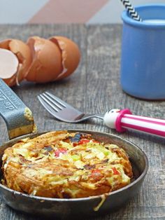 an omelet is sitting in a pan next to eggs and utensils