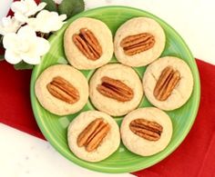 a green plate filled with almonds on top of a red and white table cloth