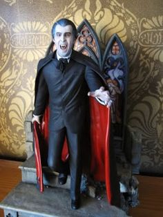 a statue of a man dressed as dracula on a red chair in front of a wall