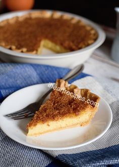 a slice of pie on a white plate with a fork and blue napkin next to it