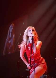 a woman standing in front of a microphone with her legs spread out on the stage