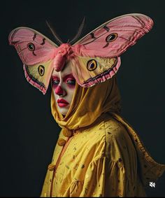 a woman wearing a butterfly mask with her face painted yellow and pink, standing in front of a black background