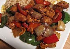 a white plate topped with meat and veggies covered in sauce next to rice