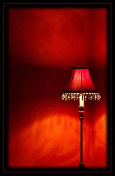 a lamp that is sitting on a table next to a red wall with the light turned on