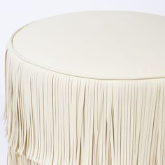 a close up of a white stool with fringes on the top and bottom part